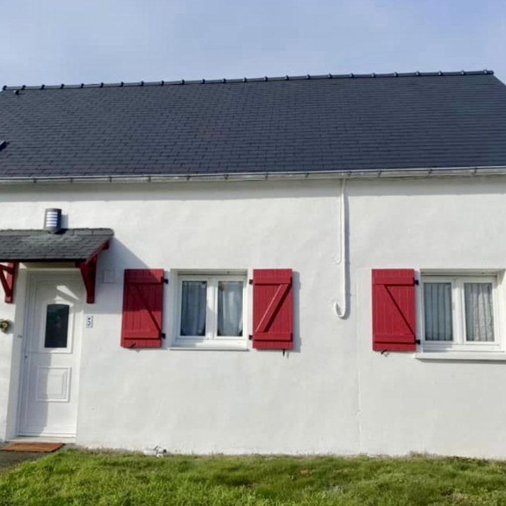 Maison après peinture de la façade et traitement de la toiture à l'hydrofuge coloré, volets rouges